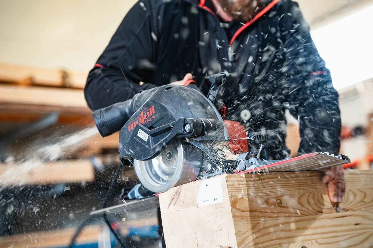 Mitarbeiter von Holzmontagebau Jurgeleit sägt Holzbalken für ein Holzbauprojekt in Roggenburg